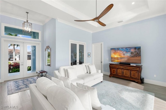 living area with french doors, visible vents, ornamental molding, baseboards, and ceiling fan with notable chandelier