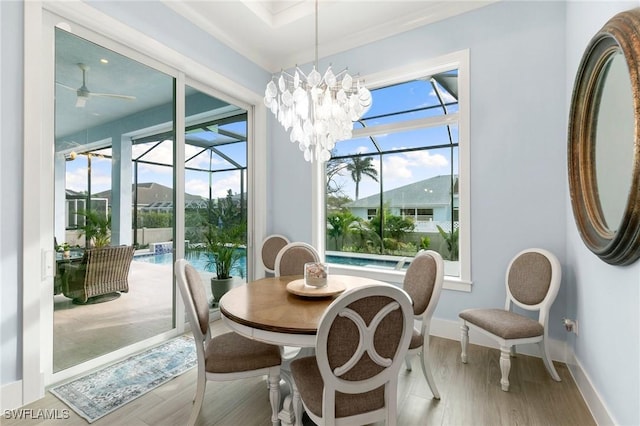 dining area with light wood-type flooring, a sunroom, baseboards, and ceiling fan with notable chandelier