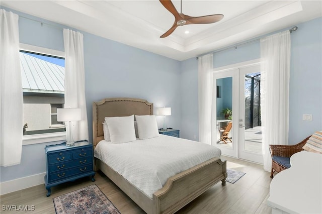 bedroom featuring access to outside, french doors, multiple windows, and a tray ceiling