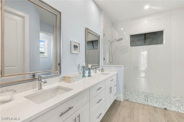 full bathroom featuring wood finished floors, double vanity, a sink, and a walk in shower