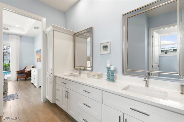 bathroom with wood finished floors, a sink, visible vents, and a healthy amount of sunlight