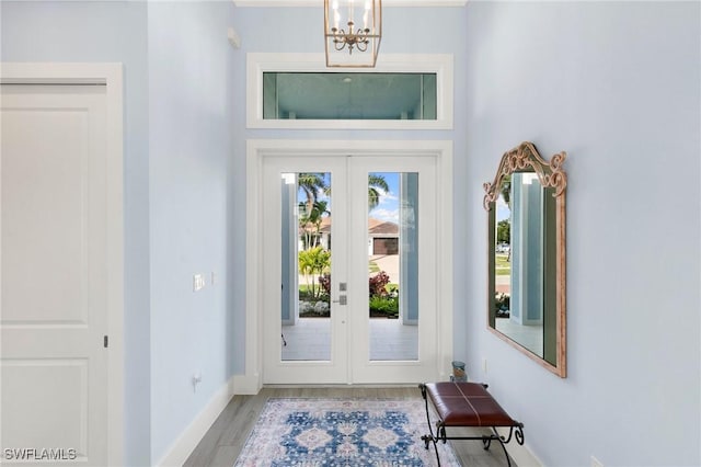 doorway to outside featuring a chandelier, french doors, wood finished floors, and baseboards