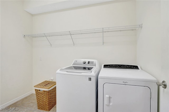 clothes washing area featuring light tile patterned floors, baseboards, laundry area, and washer and clothes dryer