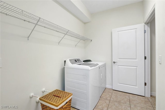 laundry area featuring baseboards, independent washer and dryer, light tile patterned flooring, and laundry area