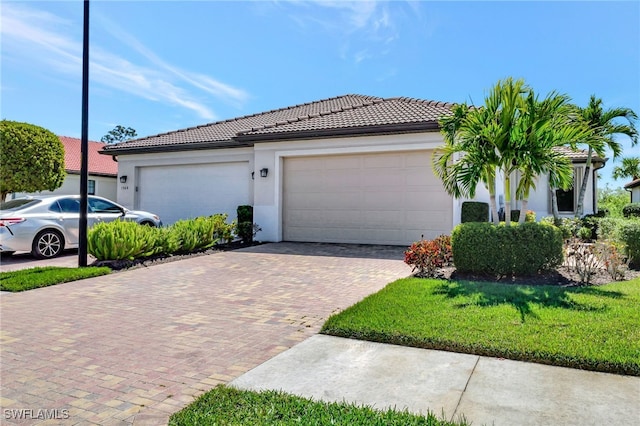 view of front of property featuring stucco siding, decorative driveway, a front yard, a garage, and a tiled roof