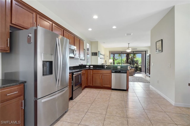 kitchen featuring recessed lighting, a peninsula, light tile patterned flooring, stainless steel appliances, and a sink