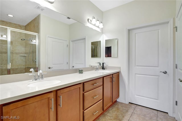 full bathroom with double vanity, a stall shower, visible vents, and a sink