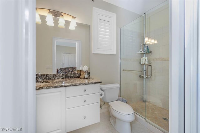 bathroom with a stall shower, vanity, toilet, and tile patterned floors