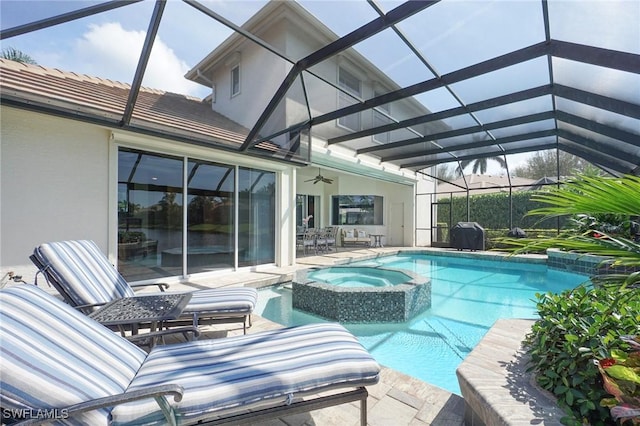 view of swimming pool with ceiling fan, glass enclosure, a patio, a pool with connected hot tub, and grilling area