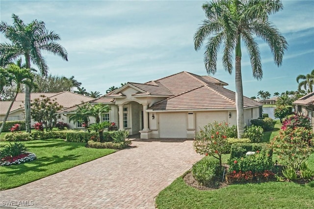 view of front of property featuring an attached garage, a tile roof, decorative driveway, stucco siding, and a front yard