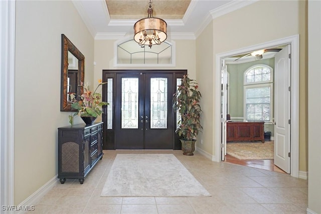 foyer with ornamental molding, french doors, light tile patterned flooring, and a raised ceiling