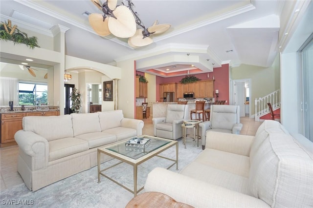 living area with a ceiling fan, a tray ceiling, light tile patterned flooring, and crown molding