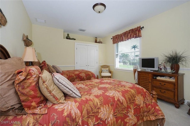 bedroom with a closet, visible vents, and light colored carpet