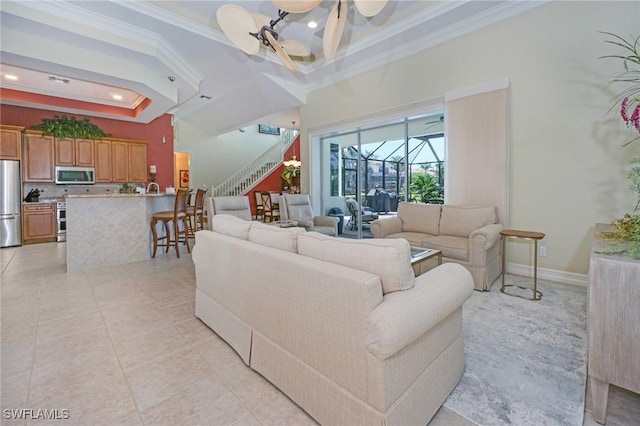 living room with ornamental molding, a towering ceiling, baseboards, and light tile patterned floors