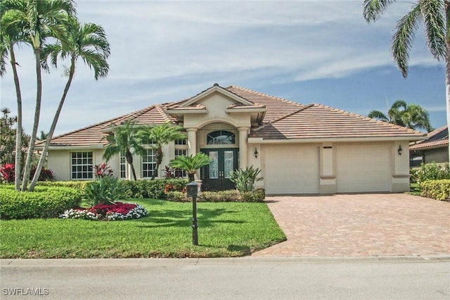 mediterranean / spanish home featuring a garage, a front lawn, decorative driveway, and stucco siding