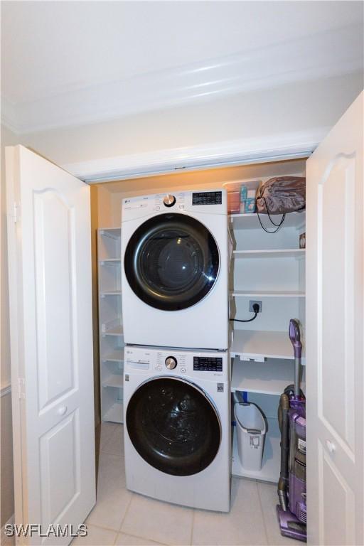 washroom featuring laundry area, stacked washer / dryer, and tile patterned flooring