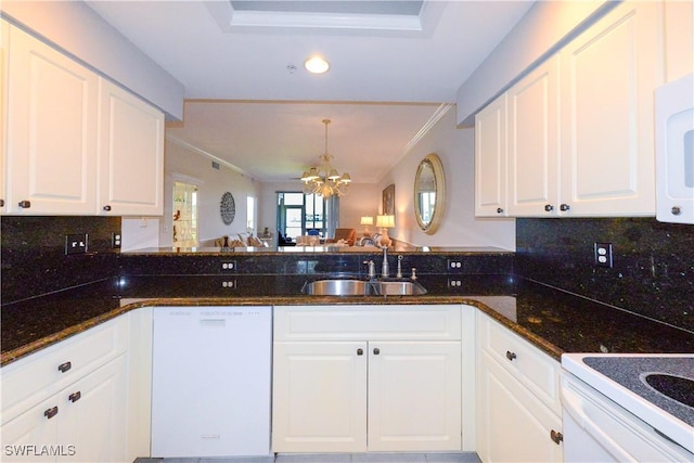 kitchen with white appliances, tasteful backsplash, a sink, white cabinetry, and a notable chandelier