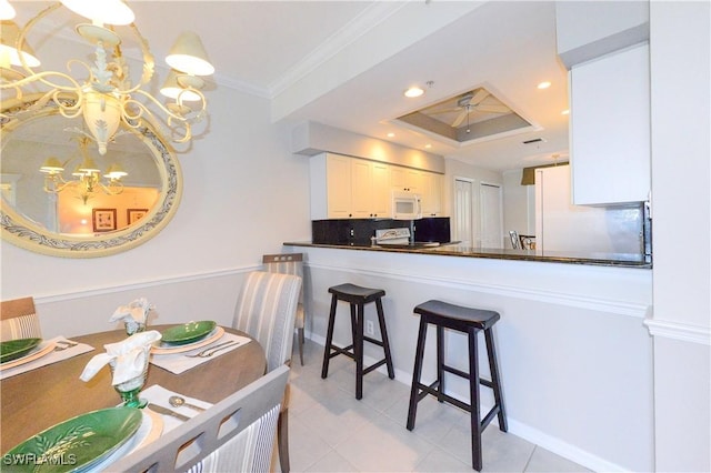 kitchen featuring white microwave, ornamental molding, backsplash, dark countertops, and an inviting chandelier