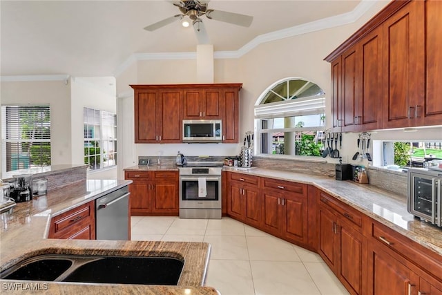 kitchen with appliances with stainless steel finishes, plenty of natural light, ornamental molding, and light tile patterned floors