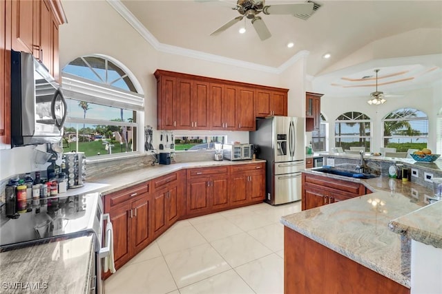 kitchen featuring light stone counters, crown molding, appliances with stainless steel finishes, a ceiling fan, and a sink