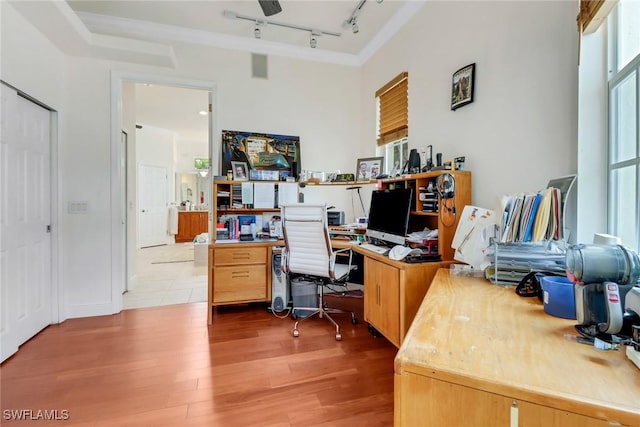 home office with light wood-style flooring and track lighting