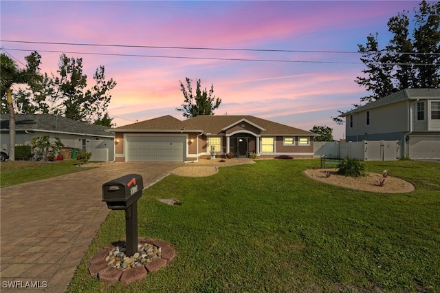 ranch-style home featuring an attached garage, a gate, fence, decorative driveway, and a front yard