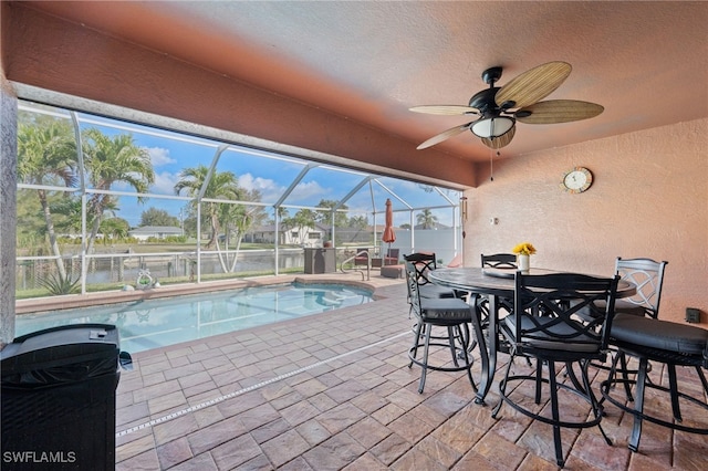 view of pool with a fenced in pool, a water view, a patio area, glass enclosure, and ceiling fan