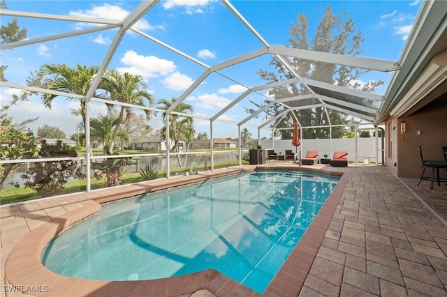 outdoor pool featuring a water view, glass enclosure, and a patio area