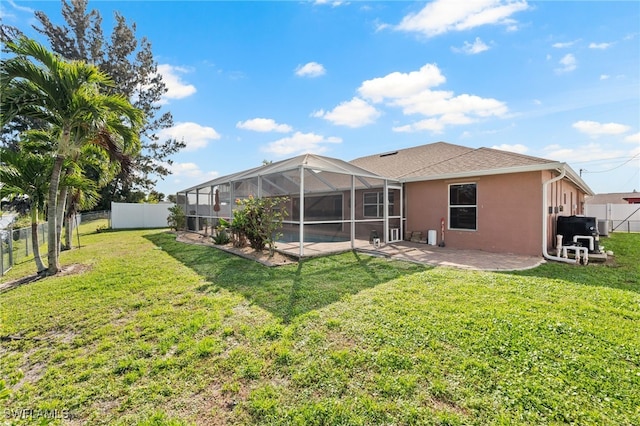 rear view of property with a patio, a fenced backyard, a lanai, a yard, and stucco siding