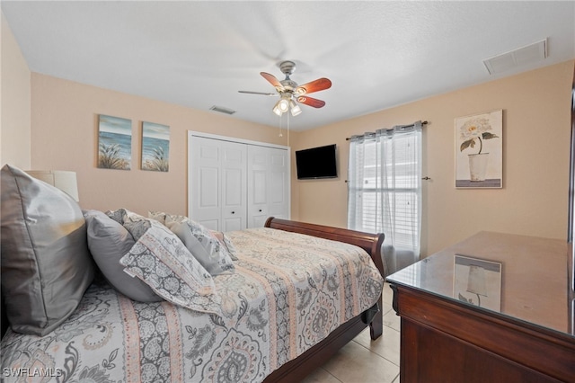 bedroom with light tile patterned floors, ceiling fan, a closet, and visible vents