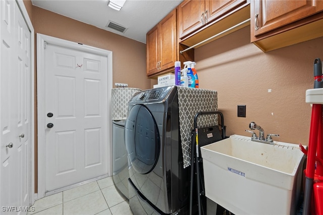 washroom featuring cabinet space, independent washer and dryer, a sink, and visible vents