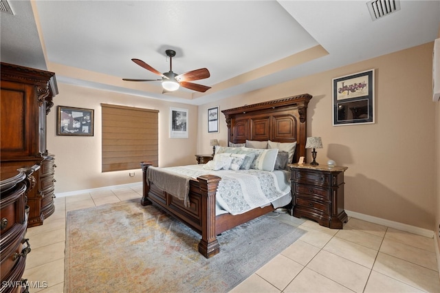 bedroom with light tile patterned floors, a tray ceiling, visible vents, and baseboards