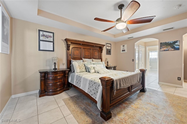 bedroom featuring arched walkways, light tile patterned flooring, a raised ceiling, and visible vents