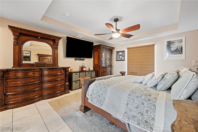 bedroom with ceiling fan, a raised ceiling, and light tile patterned flooring