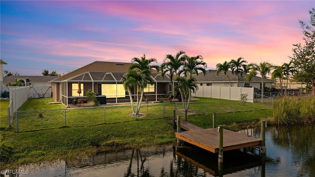 dock area featuring glass enclosure, a yard, a water view, and a fenced backyard