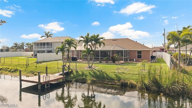 rear view of house featuring a yard, glass enclosure, a water view, and a fenced backyard