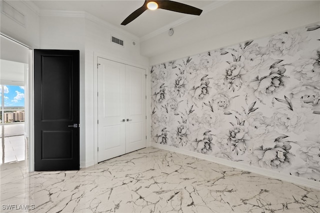 unfurnished bedroom featuring marble finish floor, a closet, visible vents, ornamental molding, and ceiling fan