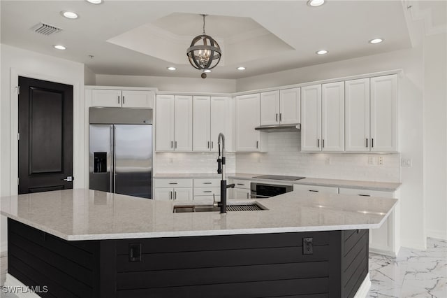 kitchen with appliances with stainless steel finishes, a large island, a raised ceiling, and white cabinetry