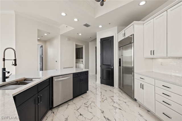 kitchen with white cabinets, stainless steel appliances, dark cabinetry, a sink, and recessed lighting