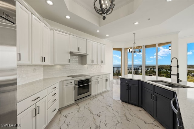 kitchen with a chandelier, dark cabinets, a sink, hanging light fixtures, and appliances with stainless steel finishes