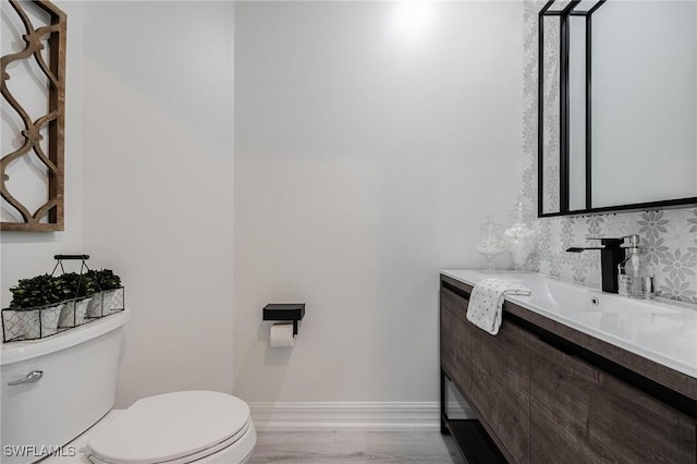 bathroom featuring baseboards, vanity, toilet, and wood finished floors