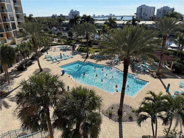 community pool featuring a view of city, a patio area, and fence