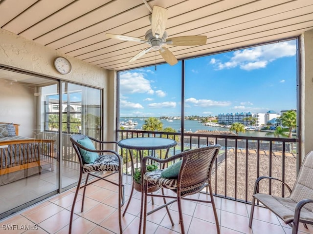 sunroom with a water view, plenty of natural light, and ceiling fan