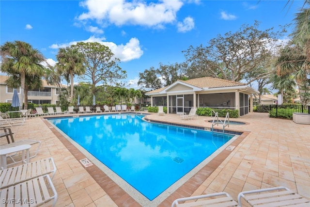 pool with a sunroom, a patio area, fence, and a community hot tub