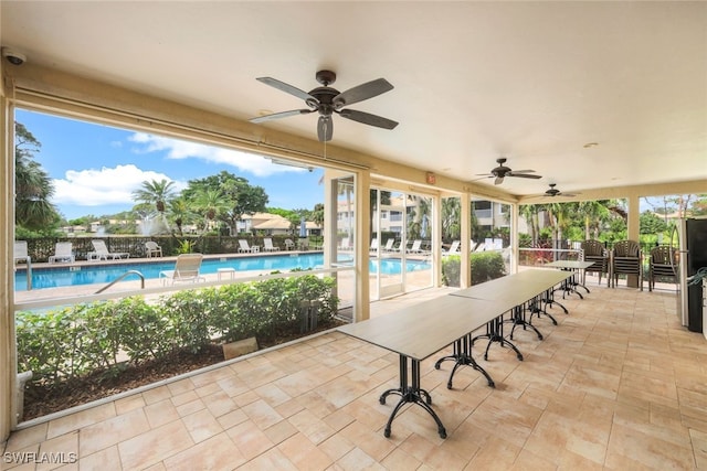 view of patio / terrace with a bar, a community pool, and a ceiling fan