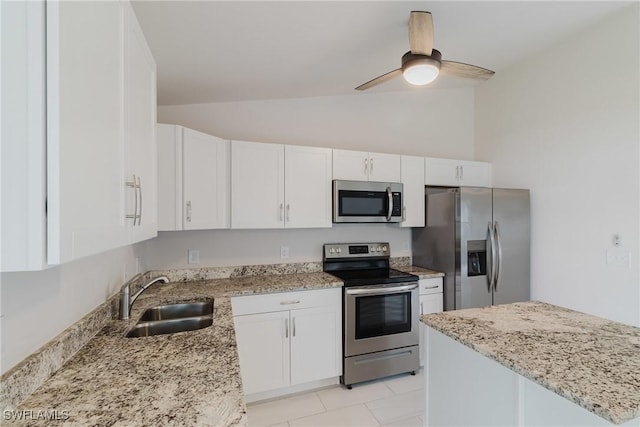 kitchen with a sink, white cabinets, appliances with stainless steel finishes, and vaulted ceiling