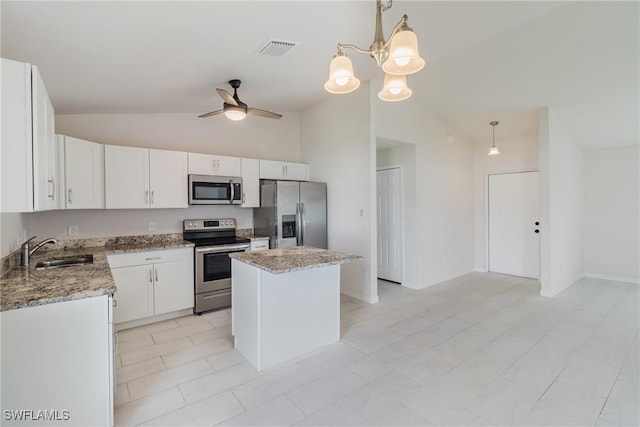 kitchen featuring stainless steel appliances, hanging light fixtures, a kitchen island, and a sink