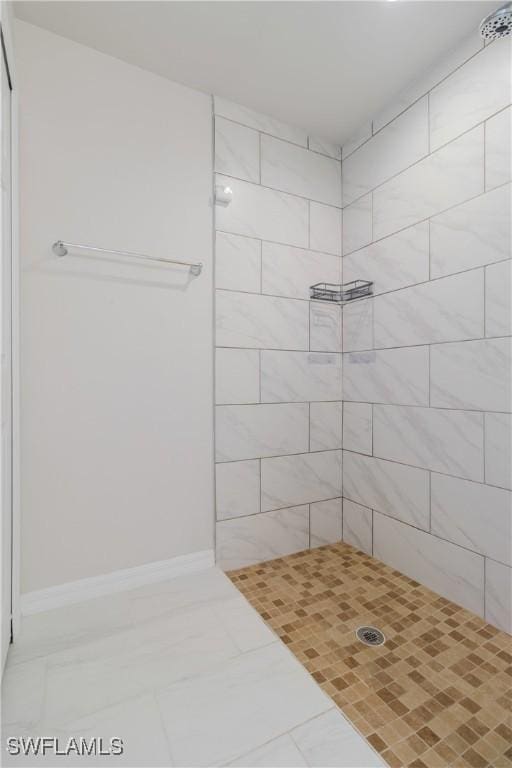 full bathroom featuring baseboards and tiled shower