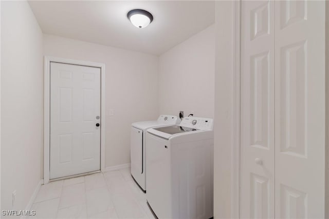 laundry room with laundry area, separate washer and dryer, light tile patterned flooring, and baseboards