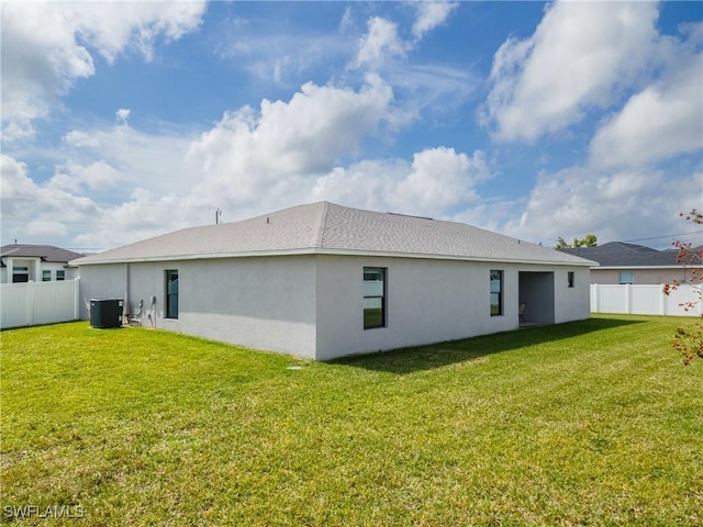 back of house with central air condition unit, a lawn, and a fenced backyard